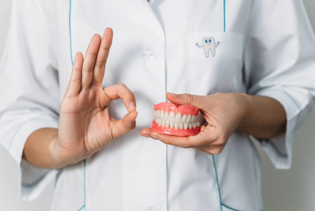 Dental prosthesis in the hands of the doctor close-up. Front view of complete denture